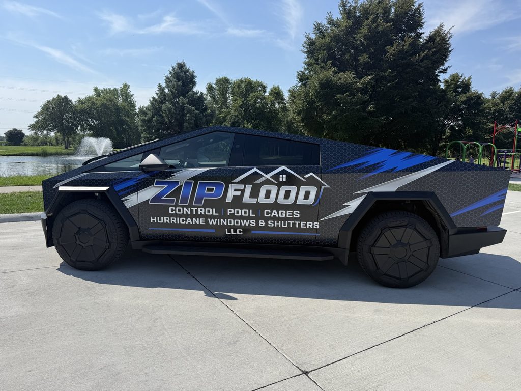 Side view of the wrapped Zip Flood Control Cybertruck at a charging station