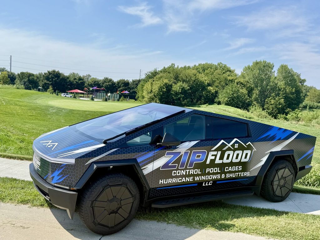 Zip Flood Control Cybertruck with company wrap on a grassy roadside